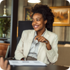 A businesswoman smiles at someone as she sits in her office. 